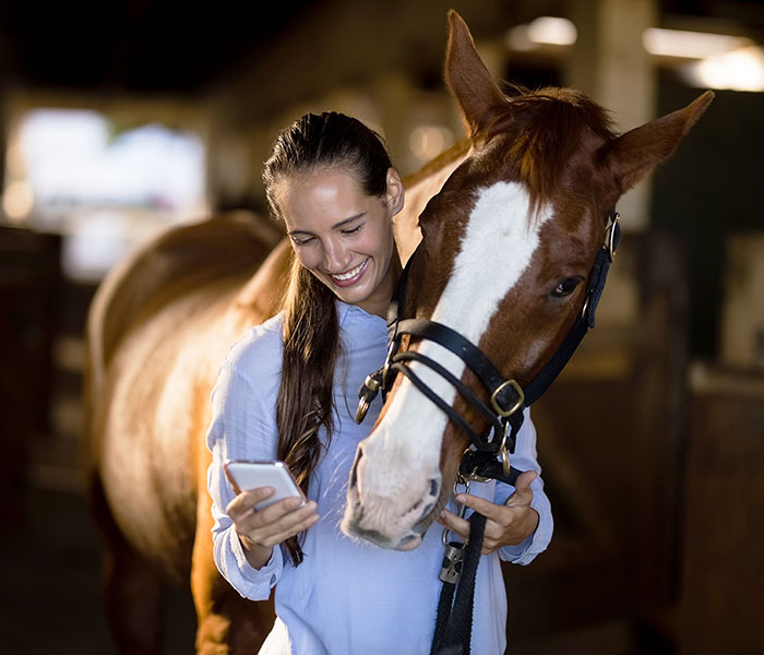 Woman with horse watching something on her phone