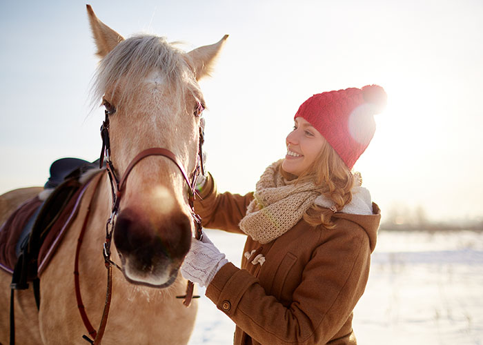 Woman in red winter hat, with palomino horse