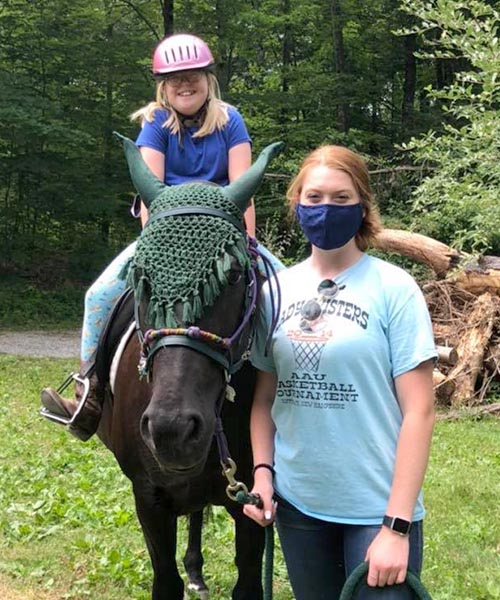 Woman with therapeutic riding participant riding a horse