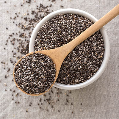 Chia seeds in wooden spoon and bowl from top view