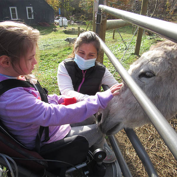Cedarcrest Center for Children with Disabilities participant petting a donkey at Amazing Grace Animal Sanctuary